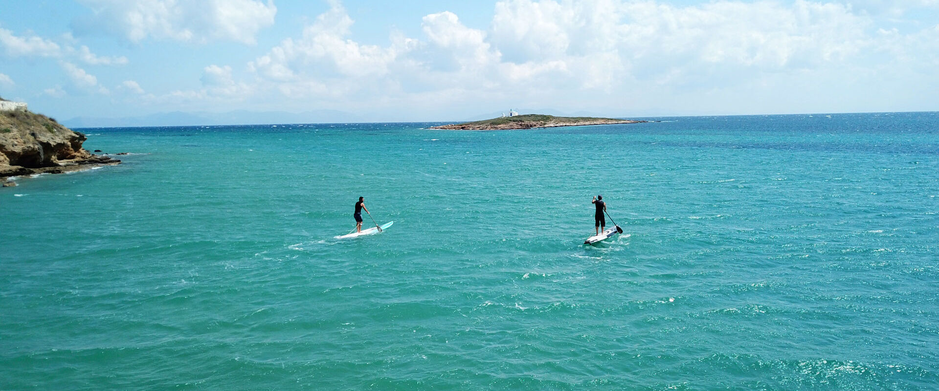Aerial photo of competition sport paddle surfing or sup between 2 men in tropical waters of Vouliagmeni beach, Athens riviera, Attica, Greece