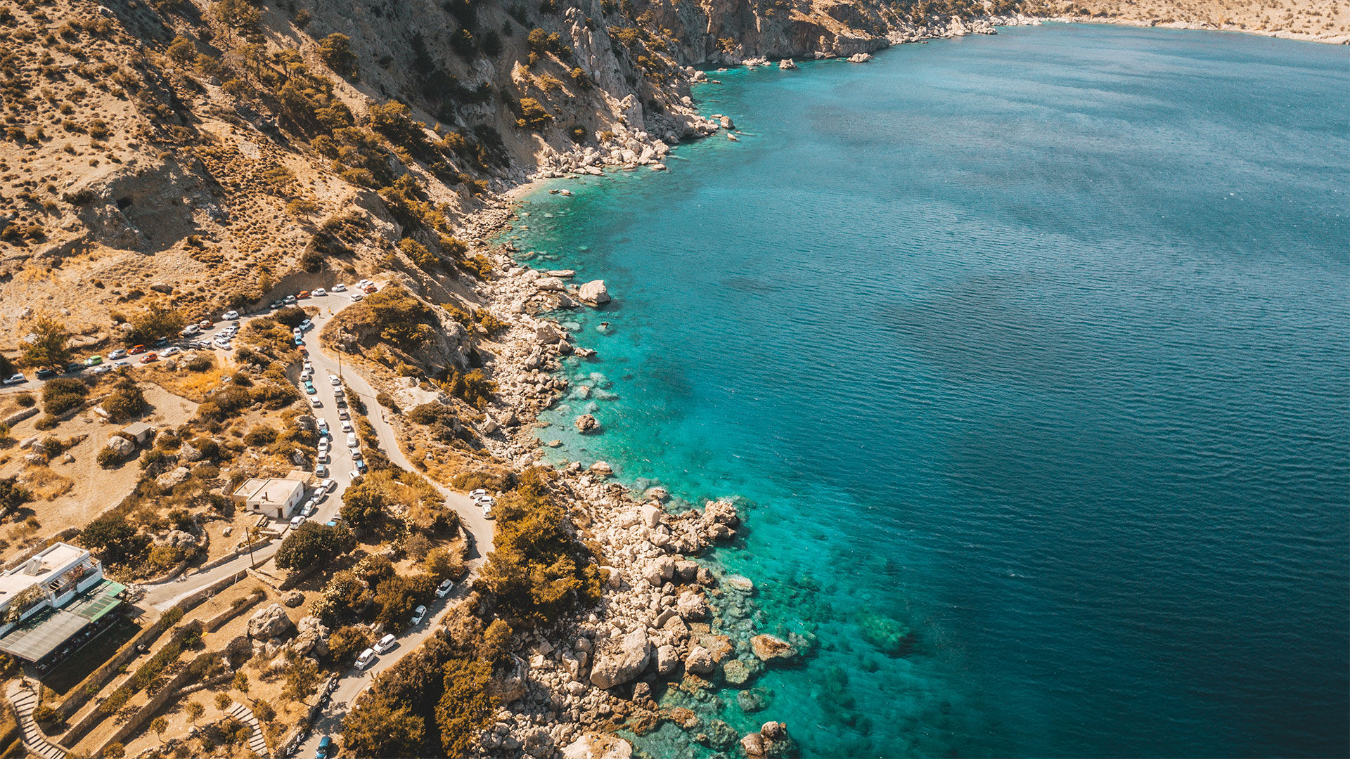 The beach is surrounded by high cliffs, mountains and lush greenery