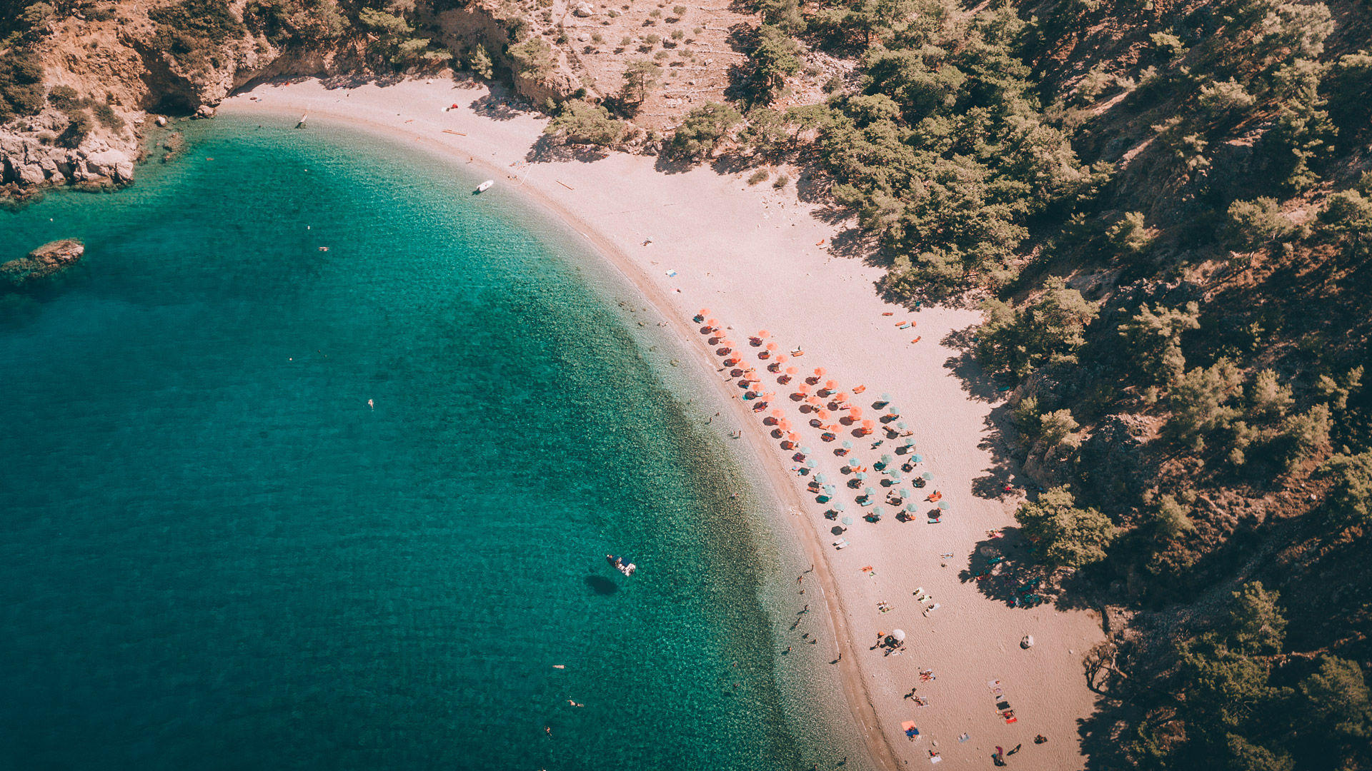 The pine trees drop right down to the beach in some places, offering natural shade that gently spreads through the afternoon