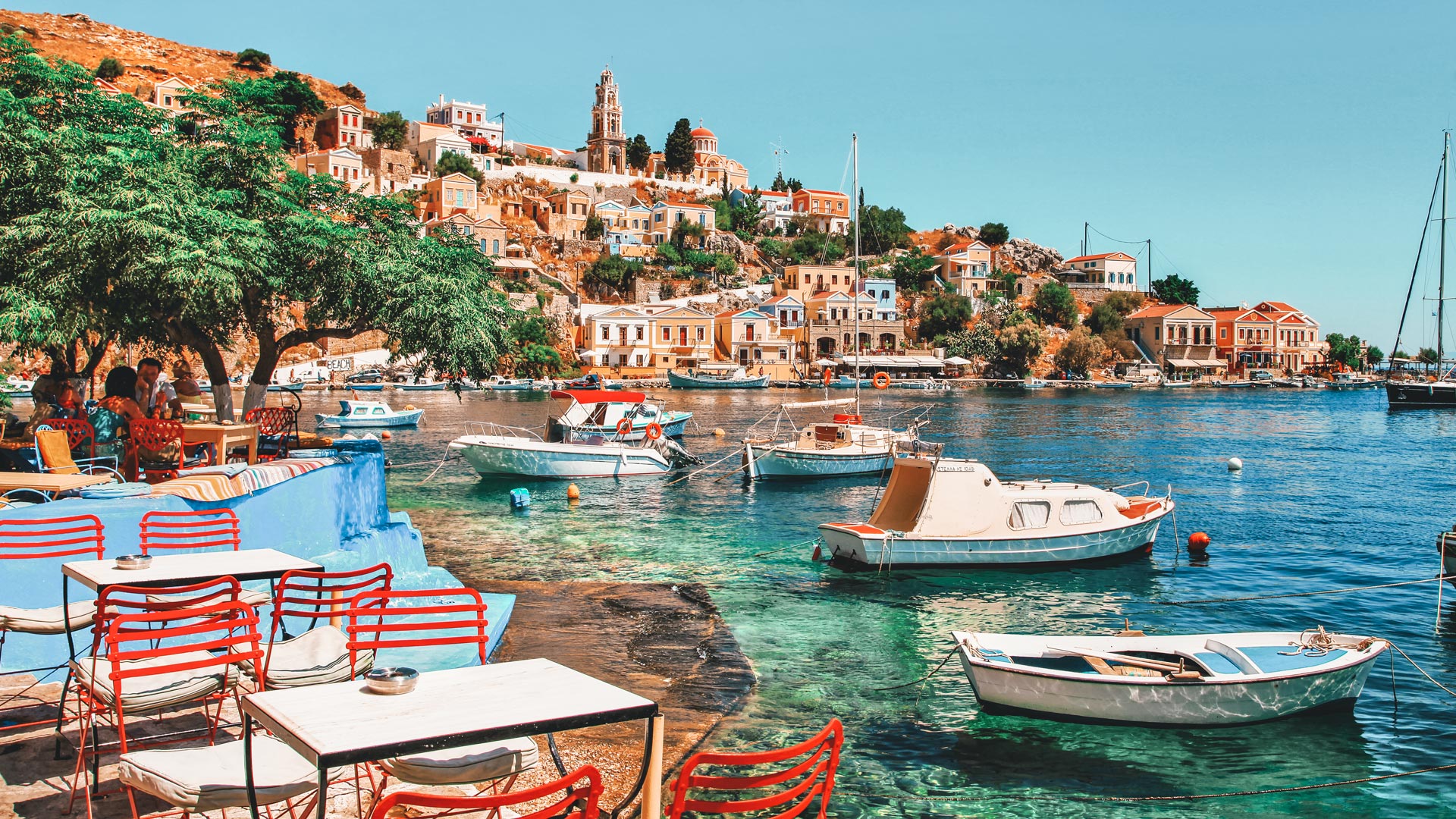 Take a look around you… at the generously-laid out tavernas and those houses rising theatrically up the hillside towards the Upper town