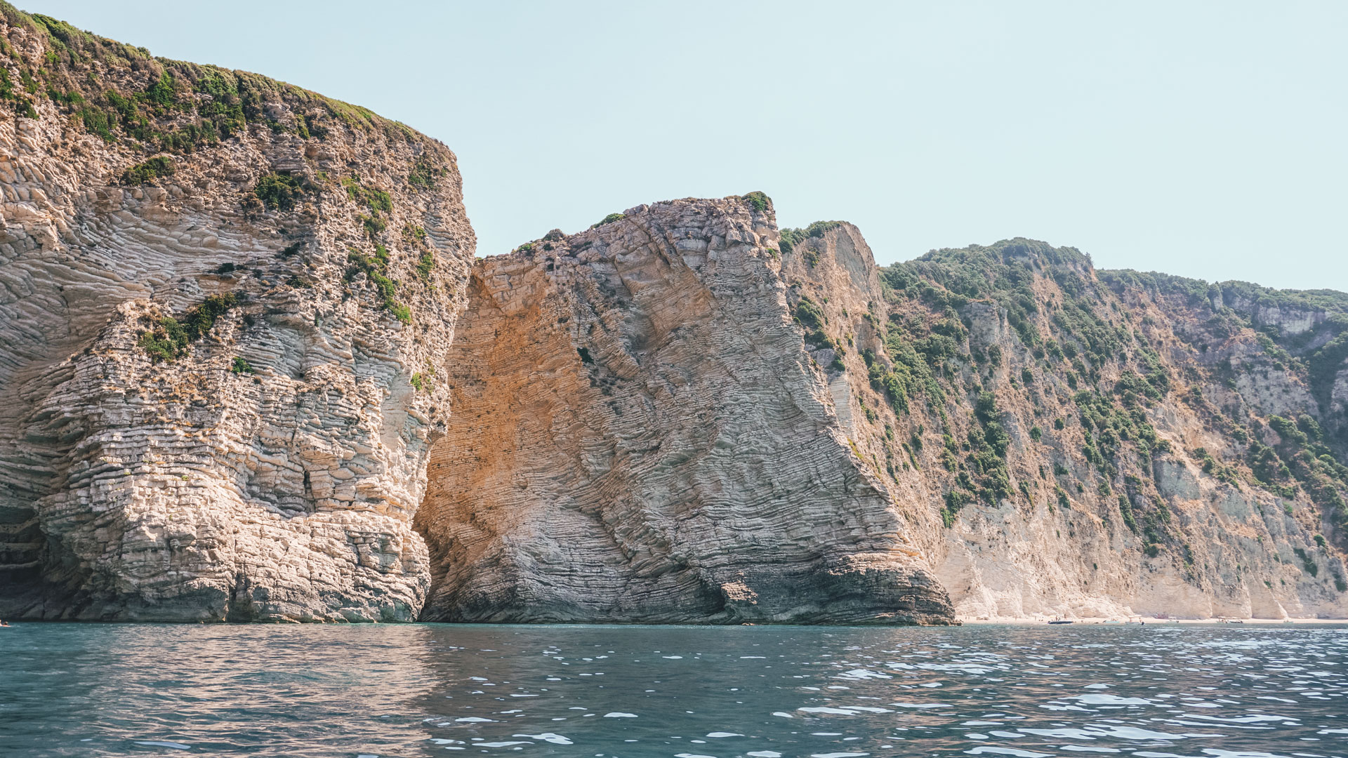 The scene is completed by the cliffs around the bay gently sloping towards the sea, carrying their carpet of greenery with them