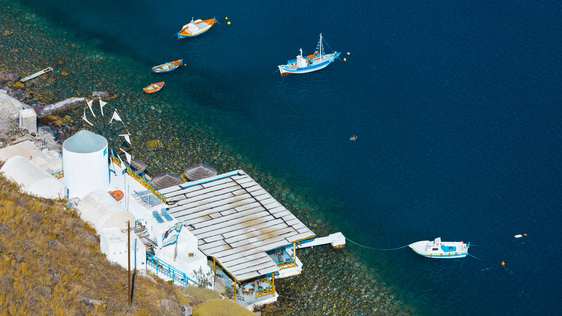 Boats and a windmill in the harbor Ormos Korfou in Thirassia seen from above