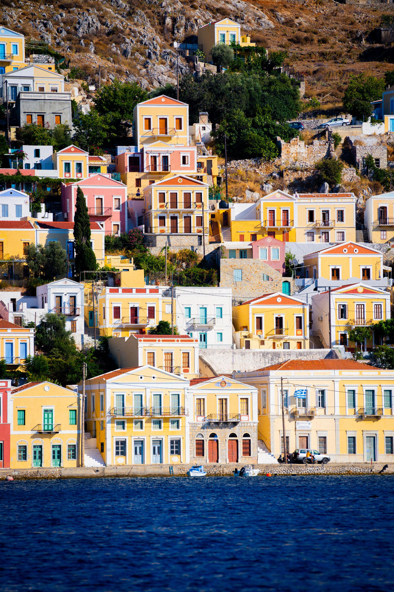 Appreciate the colours and grandeur of the mansion houses rising up the hill in Gialos