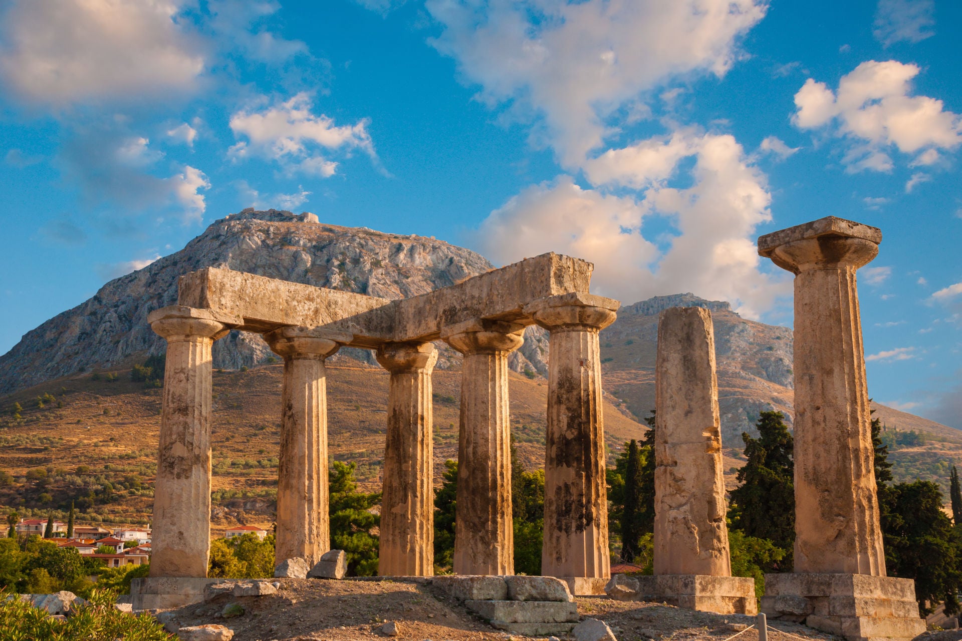 Ruins of Appollo temple with fortress at back in ancient Corinth