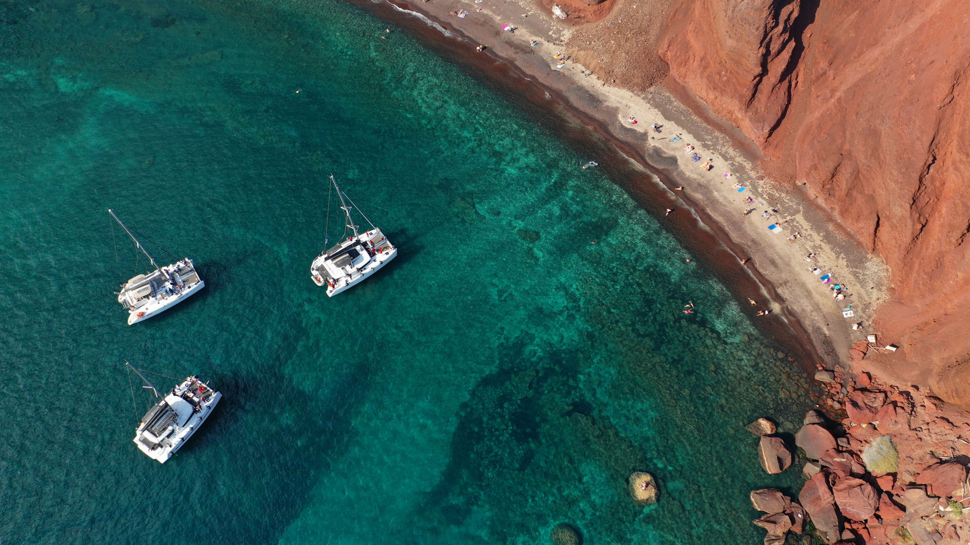 Aerial drone top down photo of iconic famous red volcanic beach and small chapel of Saint Nikolas, Santorini island