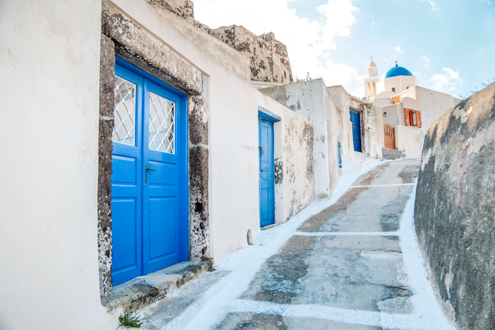 Beautiful street with blue doors of Akrotiri in Santorini
