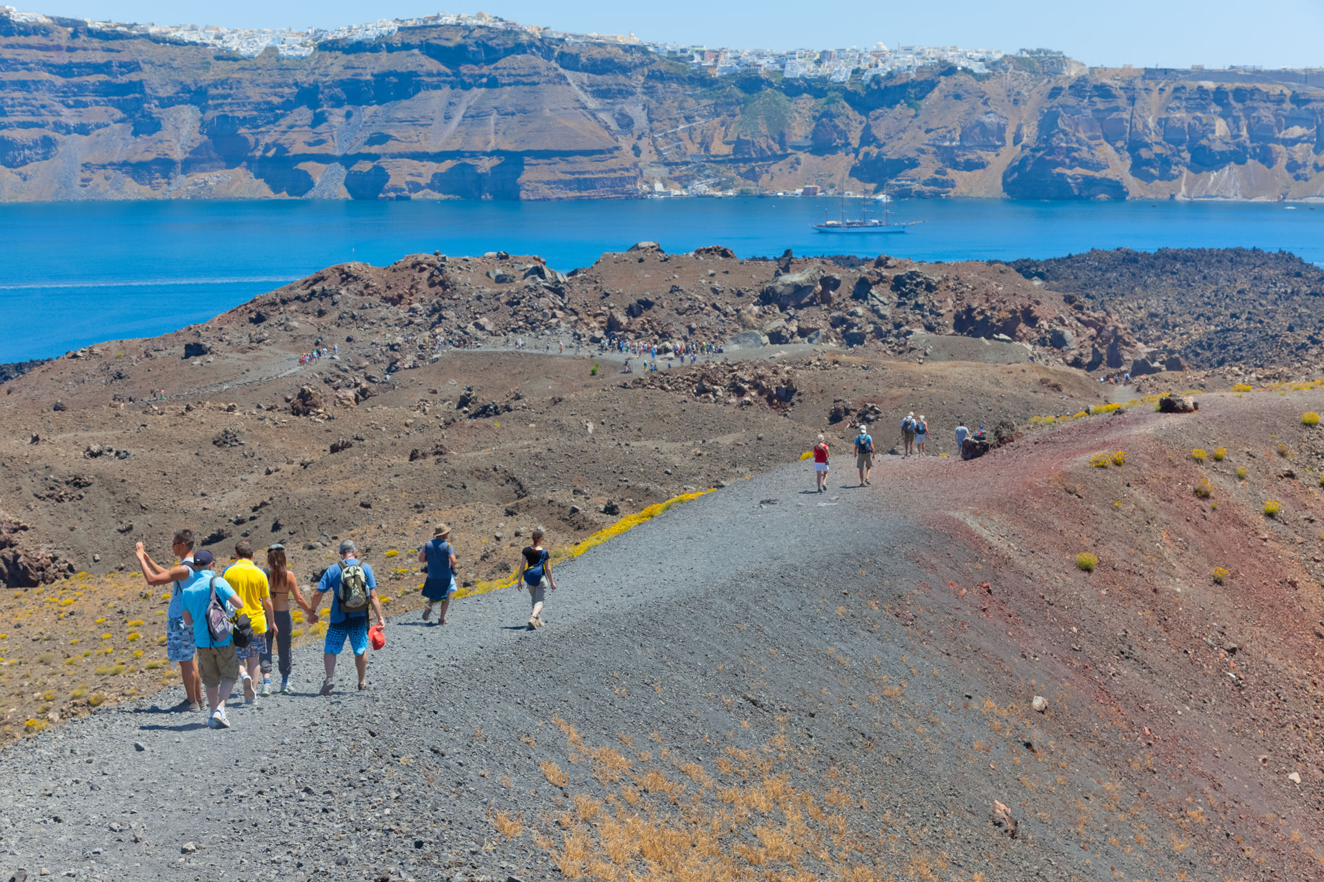 Tourist walking to volcano island in Santorini, Greece