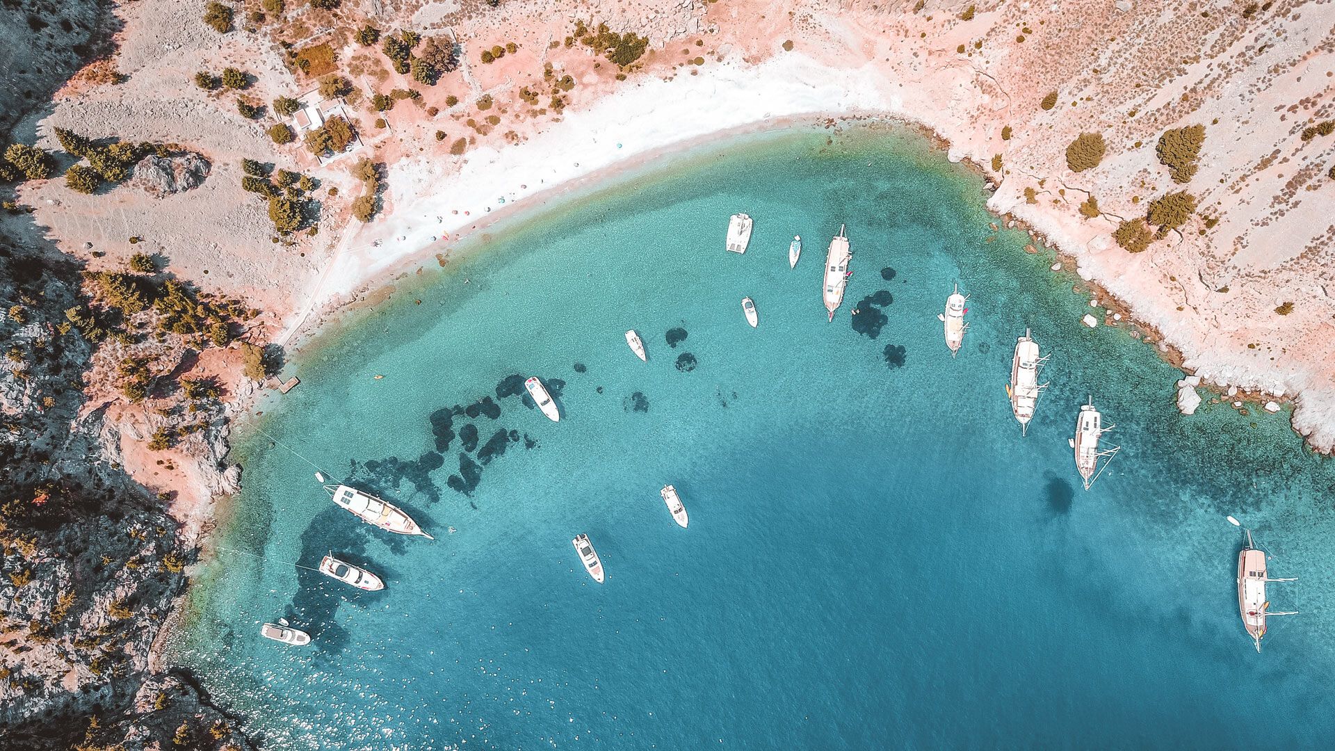 The famous tropical rocky beach of Agios Georgios with yachts docked, Symi island, Dodecanese
