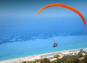 The sight of the paragliders, who launch from the green mountain backdrop and arc overhead before settling on the beach