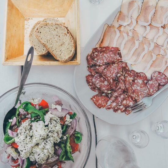 A delicious country sausage or syglino (small pieces of cured pork), accompanied with Greek salad and raki