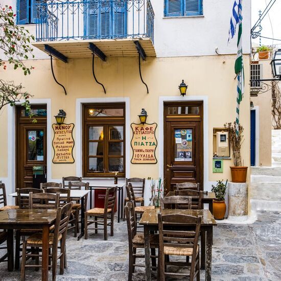 Traditional coffee shop and tavern with wooden old style chairs and tables at Chora Ioulis