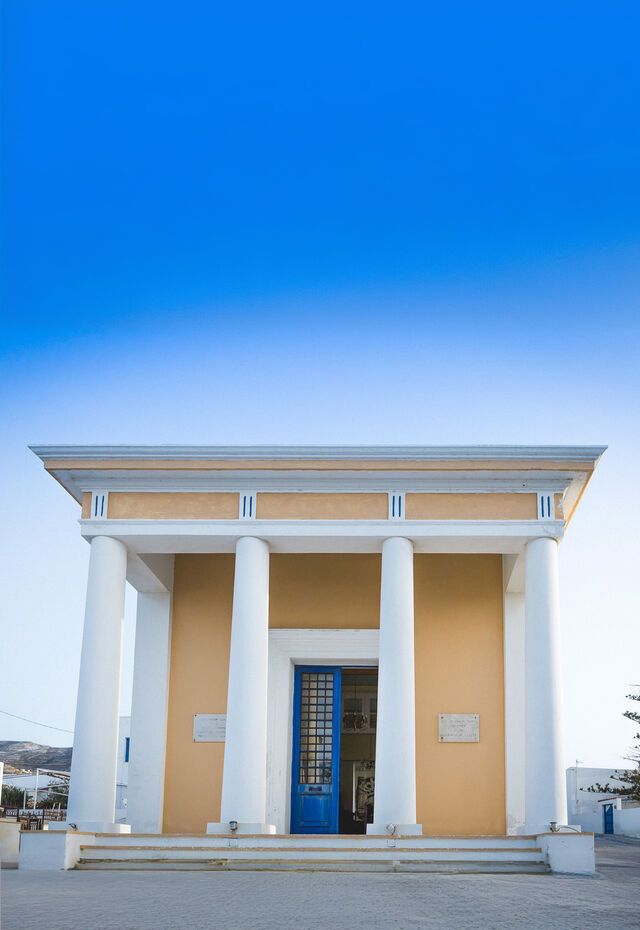 Neoclassical building with white columns and a blue door in Kasos.