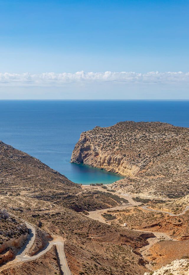 Winding road leading to a secluded bay with turquoise water in Kasos.