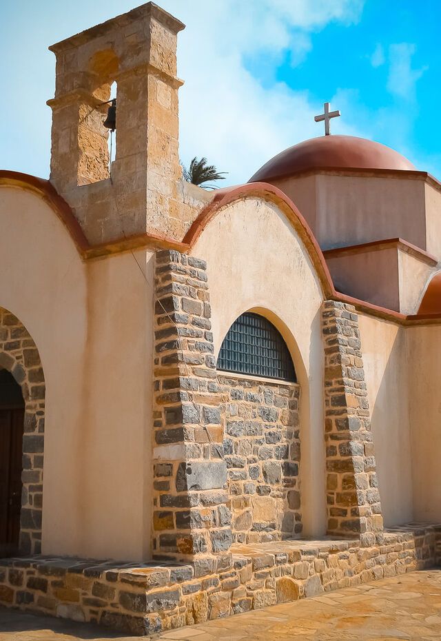Eine traditionelle Steinkirche mit gewölbten Portalen und einem Glockenturm auf der Insel Kasos.