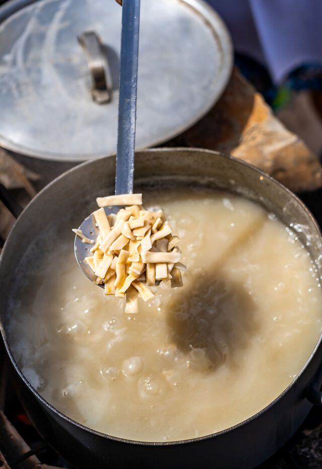 Close-up of a pot boiling a traditional dish, with pasta being added, highlighting Kasos Island's gastronomy.