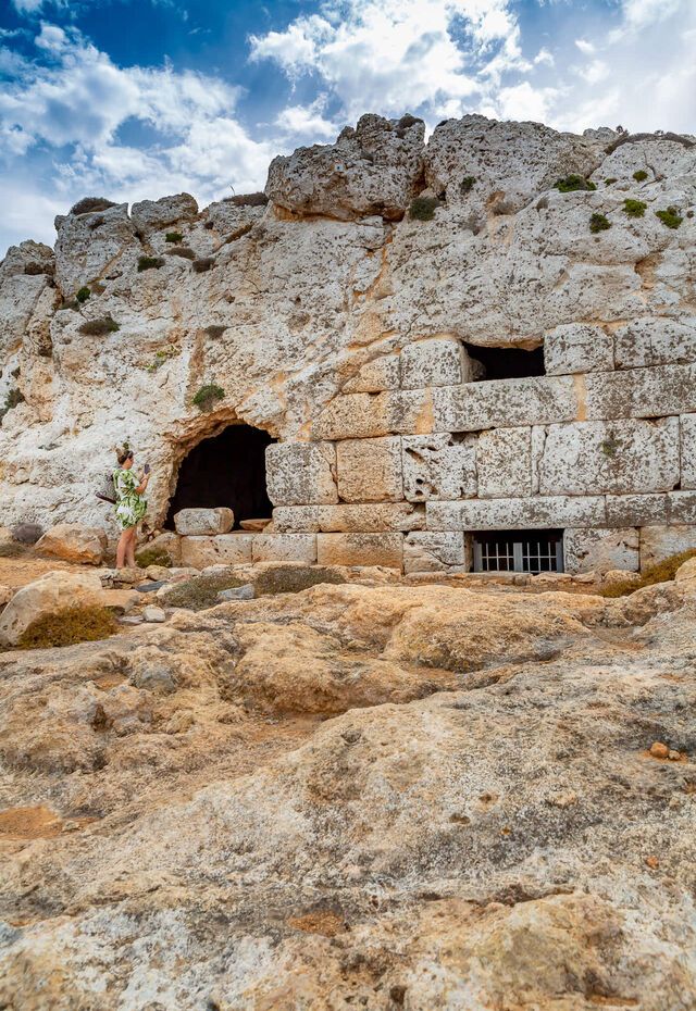 Ellinokamara Cave in Kasos, with a woman exploring the site.