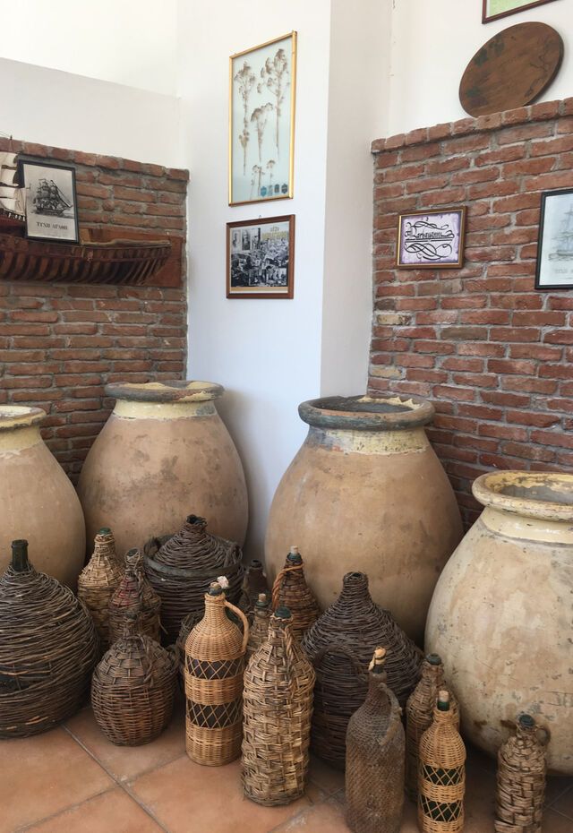 Traditional clay jars and wicker bottles on display at the Ouzo Varvagianni Museum, Lesvos