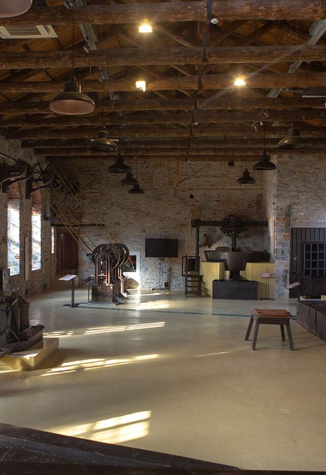 The Vranas Olive Press and Museum interior with historic olive-oil machinery and belt-driven equipment inside the stone-built hall.