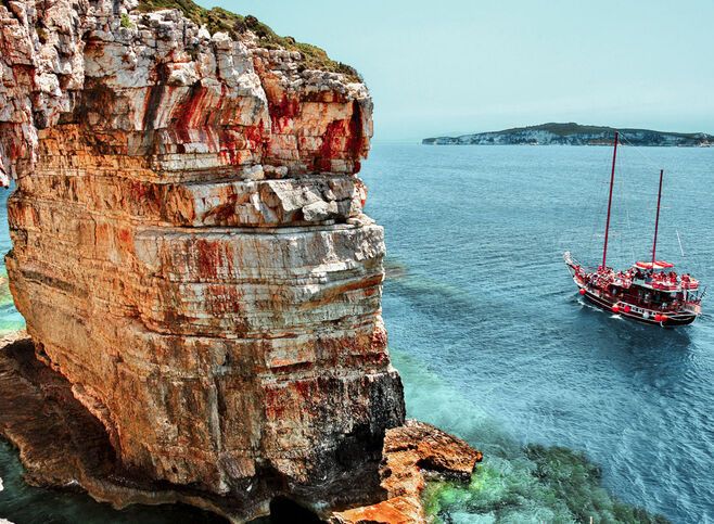 Boat passing next to Trypitos (also known as Kamara), a natural rocky arch at Paxos island