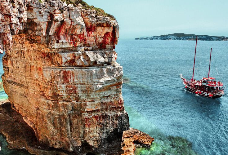 Boat passing next to Trypitos (also known as Kamara), a natural rocky arch at Paxos island