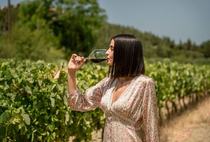 A woman tasting wine in a vineyard in Kefalonia