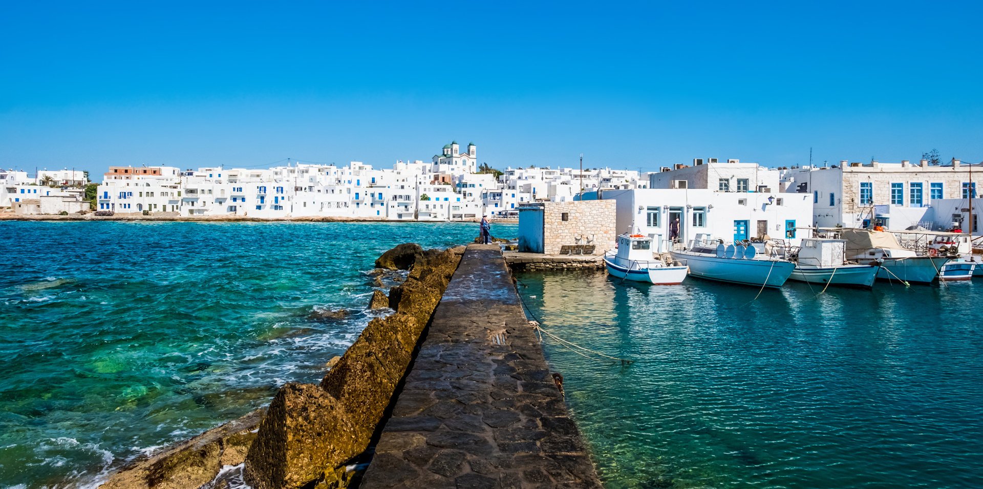 View of the traditional white houses on the promenade of Naoussa Paros, from the harbor on a sunny day