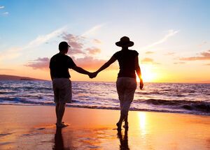 Paare, die Sonnenuntergang am Strand genießen